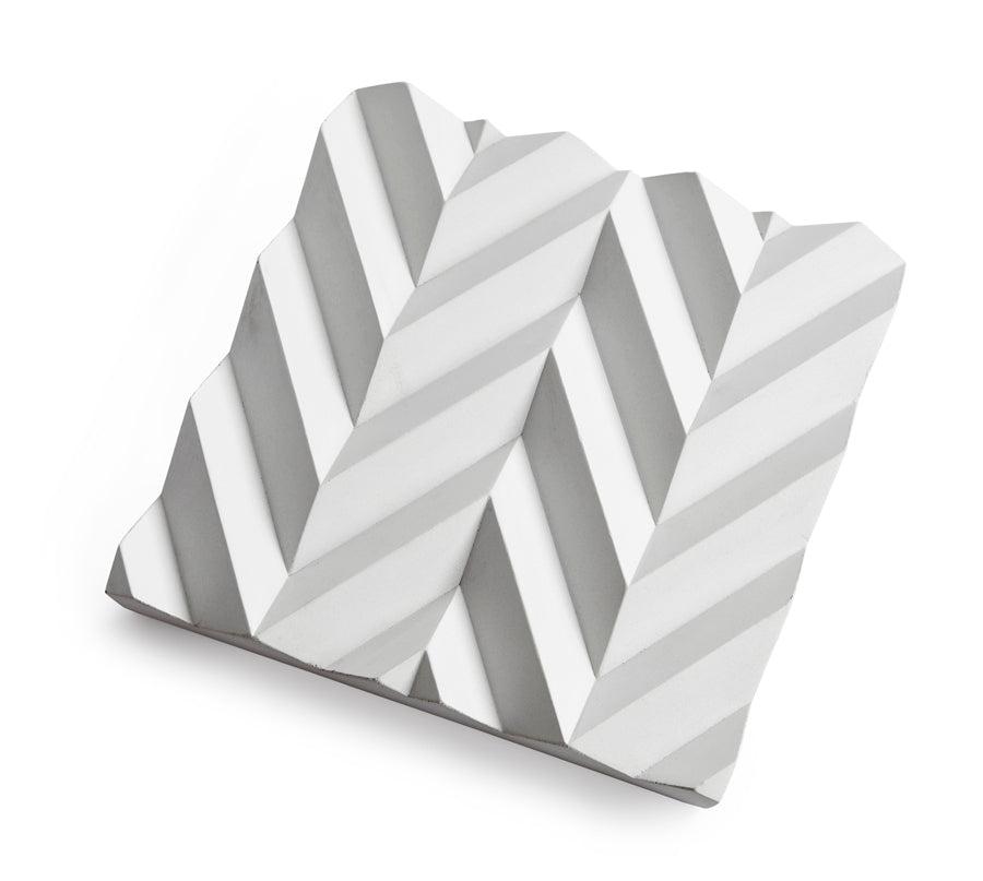 Vitt fat i betong.Ett fat från Tove Adman inspirerat av origamivikning. Reliefen gör att exempelvis frukt håller sig bättre pga luft underifrån. Dekorativt fat. Vit keramik.